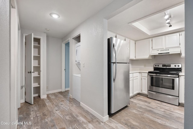 64 Winterbrook Way Unit 101, Sandpoint, ID 83864 - kitchen with appliances with stainless steel finishes, under cabinet range hood, estacked washer and dryer, light wood-style floors, and white cabinets