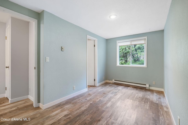 64 Winterbrook Way Unit 101, Sandpoint, ID 83864 - unfurnished bedroom with a baseboard heating unit, wood finished floors, and baseboards
