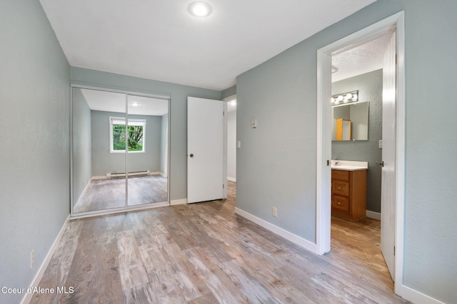 64 Winterbrook Way Unit 101, Sandpoint, ID 83864 - unfurnished bedroom with light wood finished floors, a baseboard heating unit, a closet, and baseboards