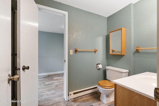 64 Winterbrook Way Unit 101, Sandpoint, ID 83864 - bathroom featuring a baseboard radiator, wood finished floors, a textured wall, toilet, and vanity