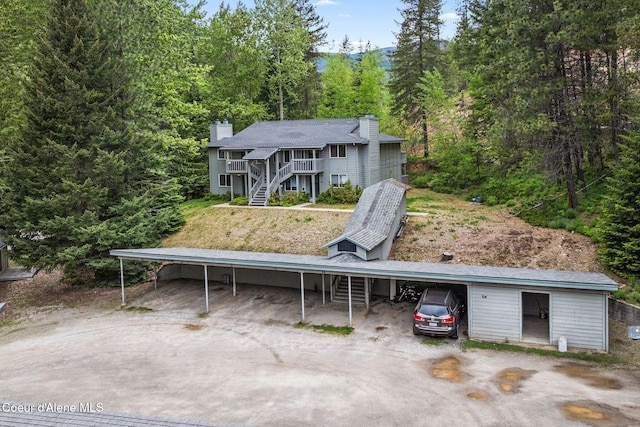 64 Winterbrook Way Unit 101, Sandpoint, ID 83864 - rear view of property with stairs, a forest view, driveway, and a wooden deck