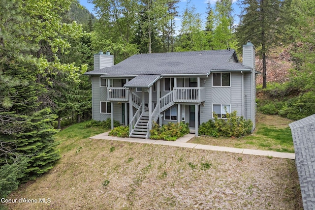 64 Winterbrook Way Unit 101, Sandpoint, ID 83864 - view of front of property with a chimney, stairway, roof with shingles, a front lawn, and covered porch