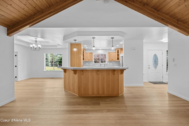 2411 W Diamond Bar Rd, Rathdrum, ID 83858 - kitchen featuring a breakfast bar, light wood-style floors, glass insert cabinets, a chandelier, and beam ceiling