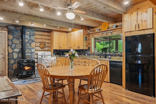 1180 Mountain View Rd, Clark Fork, ID 83811 - dining area with wooden ceiling with exposed beams, light wood-style floors, a wood stove, rustic walls, and a ceiling fan