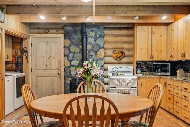 1180 Mountain View Rd, Clark Fork, ID 83811 - dining area with log walls, washing machine and clothes dryer, light wood-type flooring, beamed ceiling, and a wood stove