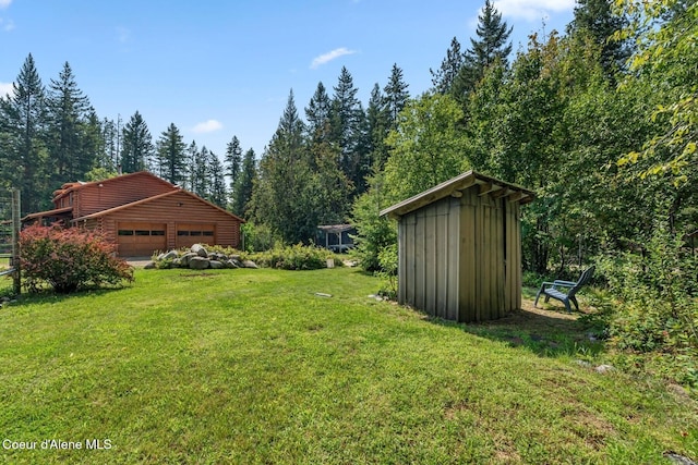 1180 Mountain View Rd, Clark Fork, ID 83811 - view of green lawn featuring an outdoor structure, an attached garage, and a wooded view