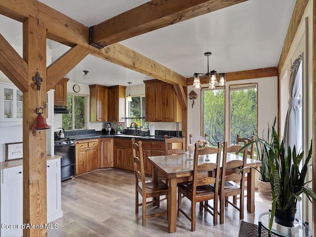 1155 Gold Creek Ridge Rd, Sandpoint, ID 83864 - kitchen with black range with gas stovetop, healthy amount of natural light, brown cabinetry, light wood-style flooring, and beamed ceiling