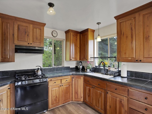 1155 Gold Creek Ridge Rd, Sandpoint, ID 83864 - kitchen with black gas stove, under cabinet range hood, a sink, and brown cabinets