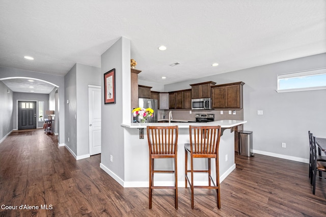 13311 N Loveland Way, Hayden, ID 83835 - kitchen with stainless steel appliances, arched walkways, light countertops, dark wood-style flooring, and a breakfast bar