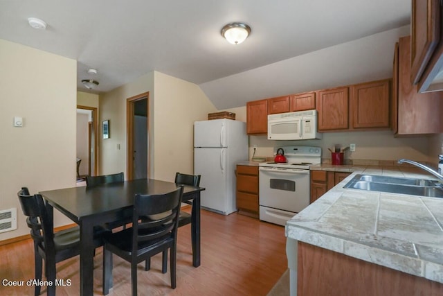 558 Grouse Hill Rd, Bonners Ferry, ID 83805 - kitchen with white appliances, a sink, brown cabinets, light wood finished floors, and lofted ceiling