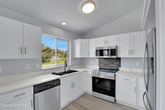 2230 N Methow Ct, Post Falls, ID 83854 - kitchen with appliances with stainless steel finishes, a sink, light stone counters, vaulted ceiling, and white cabinetry