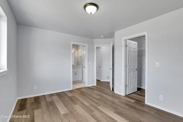 2230 N Methow Ct, Post Falls, ID 83854 - unfurnished bedroom with wood finished floors, baseboards, a walk in closet, and ensuite bath