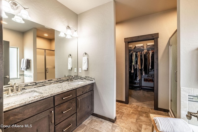 14441 N Pristine Cir, Rathdrum, ID 83858 - bathroom with a stall shower, double vanity, a walk in closet, baseboards, and a textured wall