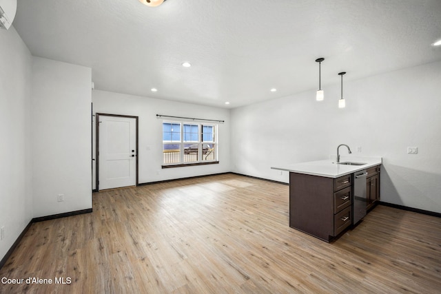 2248 N Syringa St, Post Falls, ID 83854 - kitchen with a peninsula, dark brown cabinetry, stainless steel dishwasher, light countertops, and light wood-style flooring