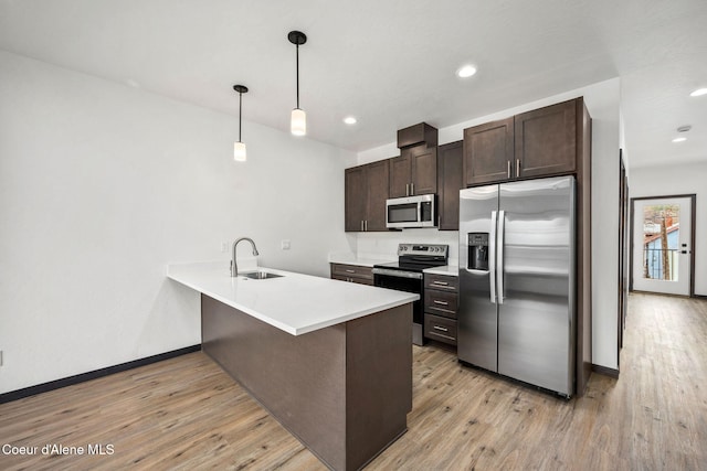 2248 N Syringa St, Post Falls, ID 83854 - kitchen featuring stainless steel appliances, a sink, dark brown cabinets, a peninsula, and light wood finished floors