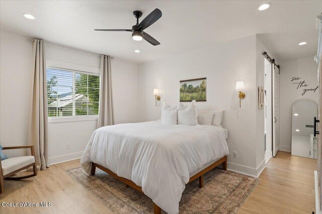 2917 N Bygone Way, Post Falls, ID 83854 - bedroom featuring a barn door, light wood-style flooring, baseboards, recessed lighting, and ceiling fan