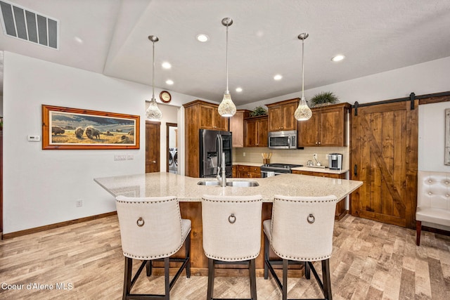 1044 E Maroon Creek Dr, Hayden, ID 83835 - kitchen with appliances with stainless steel finishes, light wood-type flooring, a sink, light stone countertops, and a kitchen bar