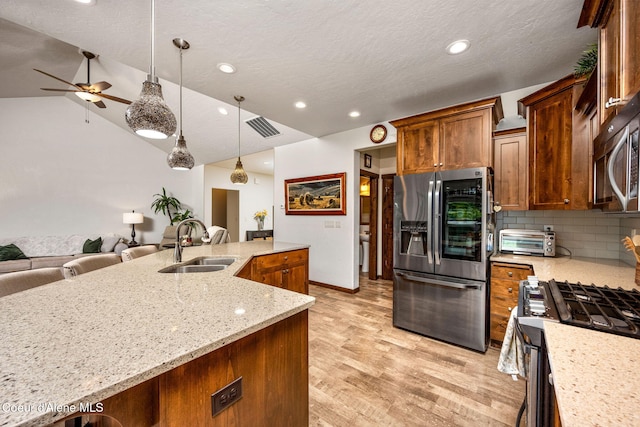 1044 E Maroon Creek Dr, Hayden, ID 83835 - kitchen featuring stainless steel appliances, a sink, open floor plan, light wood finished floors, and decorative backsplash