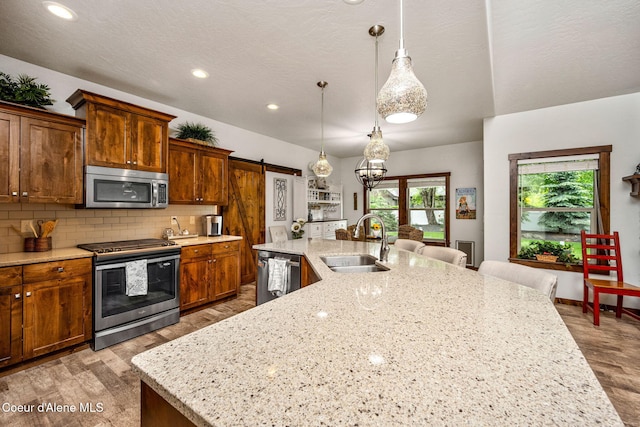 1044 E Maroon Creek Dr, Hayden, ID 83835 - kitchen with appliances with stainless steel finishes, a sink, a barn door, a spacious island, and tasteful backsplash