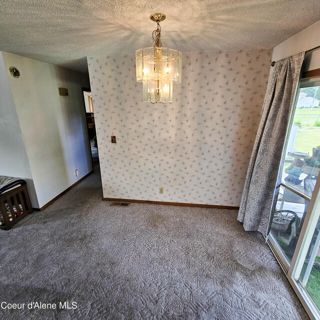 8705 N Ramsey Rd, Hayden, ID 83835 - unfurnished dining area with a textured ceiling, a chandelier, carpet floors, and baseboards