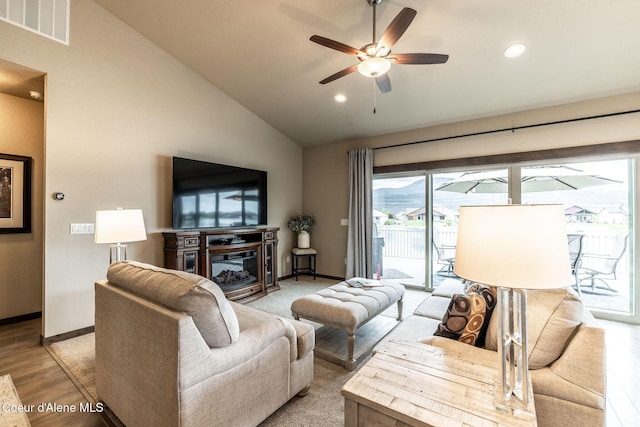 14441 N Pristine Cir, Rathdrum, ID 83858 - living room featuring vaulted ceiling, light wood finished floors, a glass covered fireplace, a ceiling fan, and recessed lighting