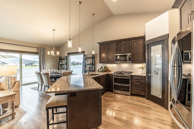 14441 N Pristine Cir, Rathdrum, ID 83858 - kitchen featuring stainless steel appliances, dark brown cabinets, a peninsula, light stone counters, and a kitchen bar