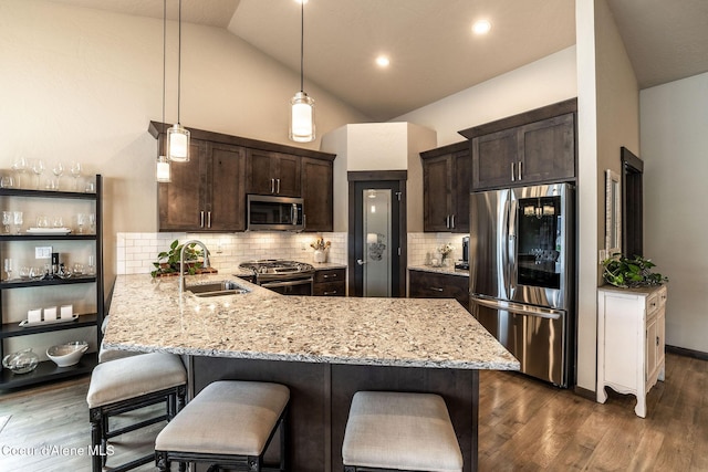 14441 N Pristine Cir, Rathdrum, ID 83858 - kitchen with stainless steel appliances, a sink, dark brown cabinetry, a kitchen bar, and light stone countertops