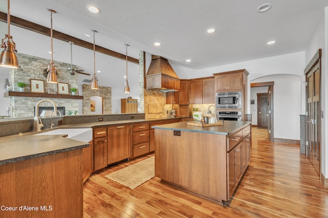 4618 S Scenic Dr, Coeur Dalene, ID 83814 - kitchen featuring appliances with stainless steel finishes, premium range hood, a sink, backsplash, and light wood-type flooring