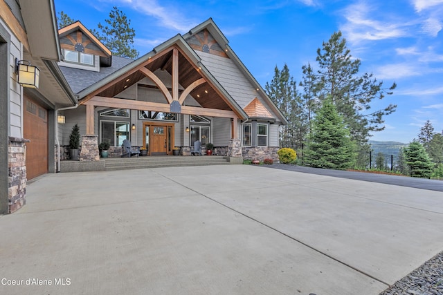 4618 S Scenic Dr, Coeur Dalene, ID 83814 - rear view of property featuring stone siding, covered porch, driveway, a mountain view, and roof with shingles