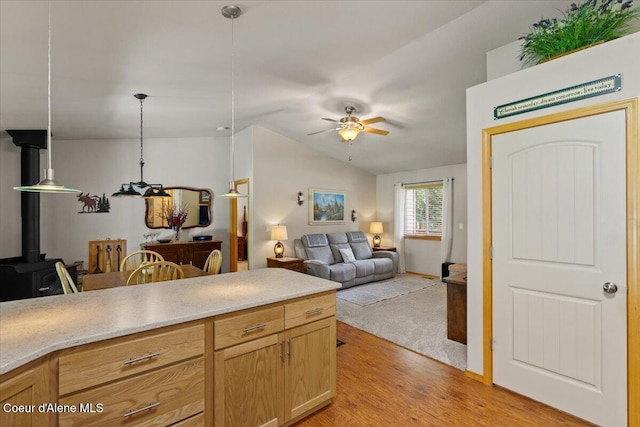 23815 N Rapalla Ct, Athol, ID 83801 - kitchen with a wood stove, ceiling fan, vaulted ceiling, light wood-style floors, and pendant lighting
