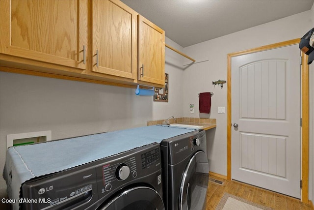23815 N Rapalla Ct, Athol, ID 83801 - washroom with cabinet space, washer and clothes dryer, light wood finished floors, and baseboards