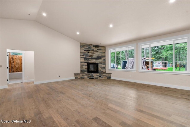 10233 Bunco Rd, Athol, ID 83801 - unfurnished living room featuring lofted ceiling, light wood-type flooring, recessed lighting, a stone fireplace, and baseboards