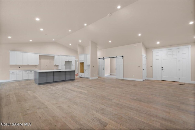 10233 Bunco Rd, Athol, ID 83801 - unfurnished living room with a barn door, light wood-style flooring, lofted ceiling, baseboards, and recessed lighting