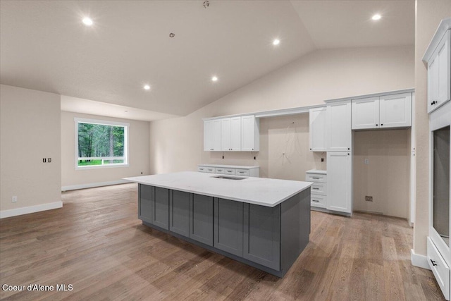 10233 Bunco Rd, Athol, ID 83801 - kitchen with gray cabinets, vaulted ceiling, an island with sink, white cabinets, and light wood-style flooring