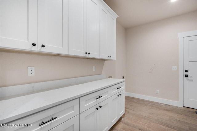 10233 Bunco Rd, Athol, ID 83801 - kitchen with light wood-style floors, white cabinets, baseboards, and light stone counters