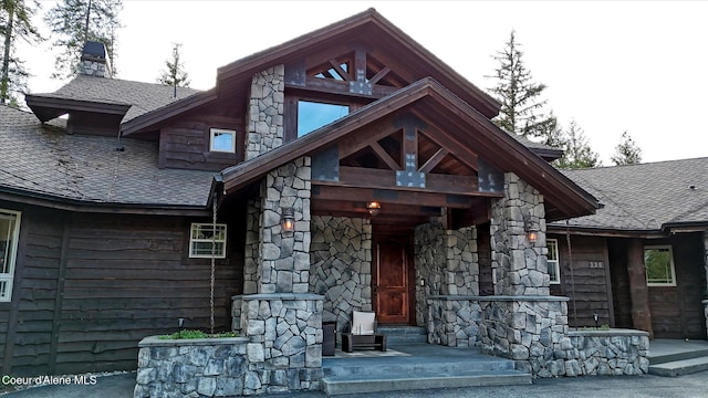 225 Fairway Dr, Priest Lake, ID 83856 - property entrance with stone siding, a chimney, roof with shingles, and covered porch