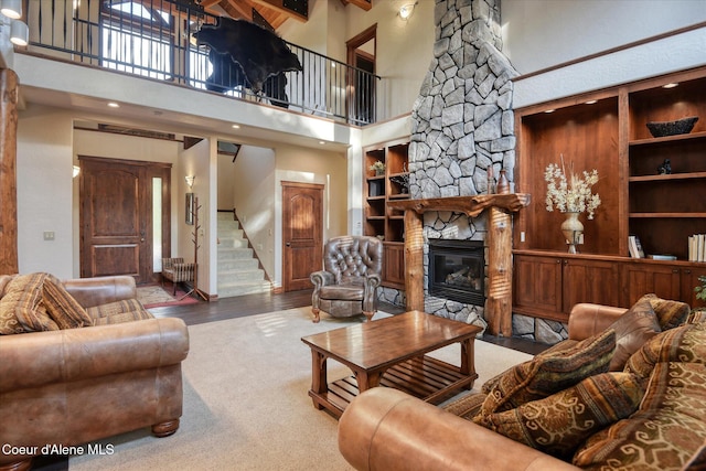 225 Fairway Dr, Priest Lake, ID 83856 - living area featuring stairs, a high ceiling, a stone fireplace, built in shelves, and carpet flooring