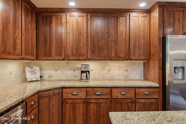225 Fairway Dr, Priest Lake, ID 83856 - kitchen with stainless steel fridge, brown cabinetry, tasteful backsplash, light stone counters, and recessed lighting