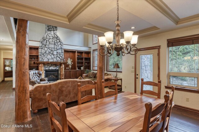 225 Fairway Dr, Priest Lake, ID 83856 - dining room with wood-type flooring, a stone fireplace, crown molding, baseboards, and a chandelier