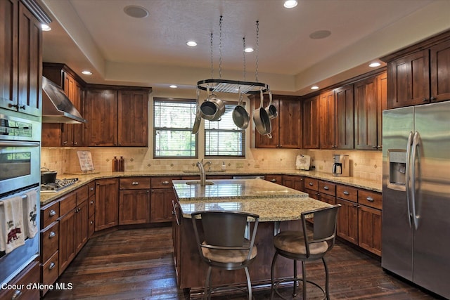 225 Fairway Dr, Priest Lake, ID 83856 - kitchen with appliances with stainless steel finishes, wall chimney exhaust hood, a center island with sink, dark wood-type flooring, and recessed lighting
