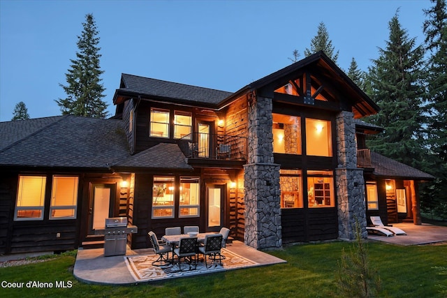 225 Fairway Dr, Priest Lake, ID 83856 - rear view of house with a balcony, a patio area, a shingled roof, and a lawn