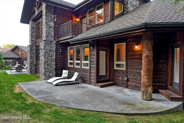 225 Fairway Dr, Priest Lake, ID 83856 - doorway to property featuring a balcony, a patio area, roof with shingles, and a yard