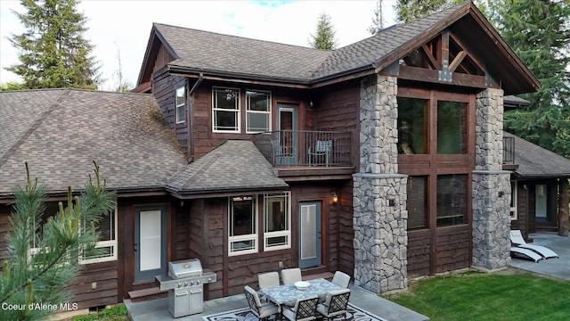 225 Fairway Dr, Priest Lake, ID 83856 - back of property with a balcony, a shingled roof, a patio, and outdoor dining space