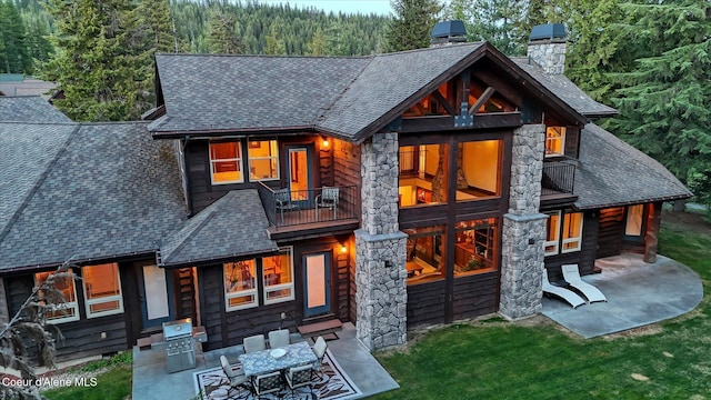 225 Fairway Dr, Priest Lake, ID 83856 - rear view of house with a shingled roof, a chimney, a balcony, and a patio area