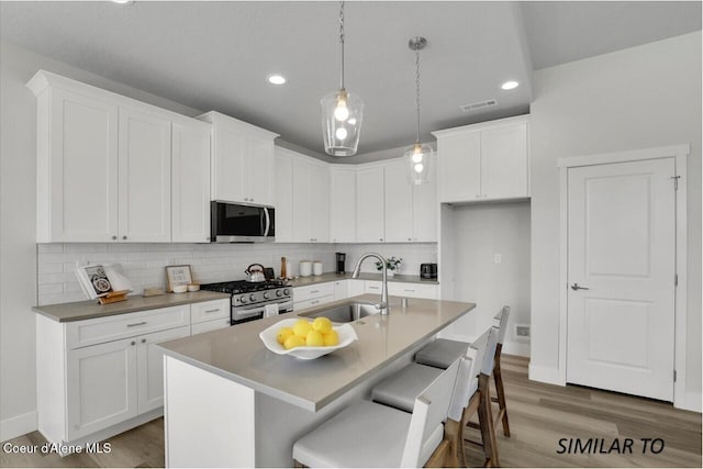 1109 N Country Club Dr Unit 22, Deer Park, WA 99006 - kitchen with appliances with stainless steel finishes, a sink, light wood-style flooring, white cabinets, and decorative backsplash