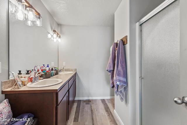 3283 N Knob Creek Ct, Post Falls, ID 83854 - full bath with wood finished floors, double vanity, a shower stall, a textured ceiling, and baseboards
