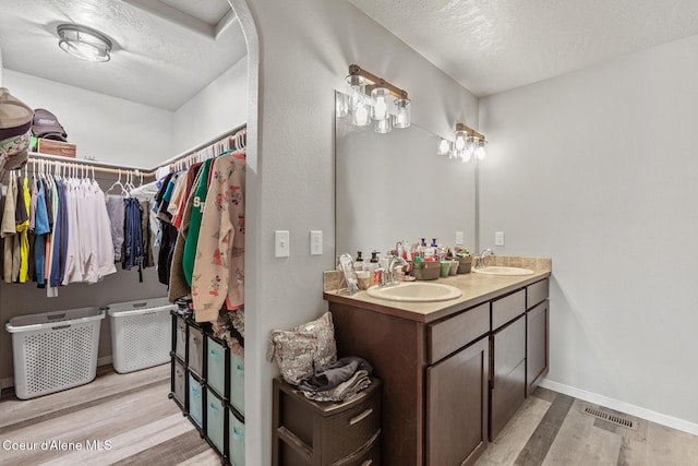 3283 N Knob Creek Ct, Post Falls, ID 83854 - full bathroom with wood finished floors, double vanity, a textured ceiling, baseboards, and a spacious closet