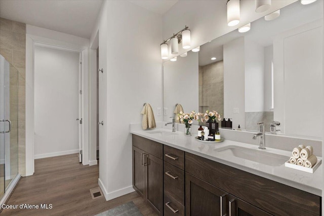 3387 N Cyprus Fox Loop, Post Falls, ID 83854 - bathroom featuring a shower stall, double vanity, wood finished floors, and baseboards