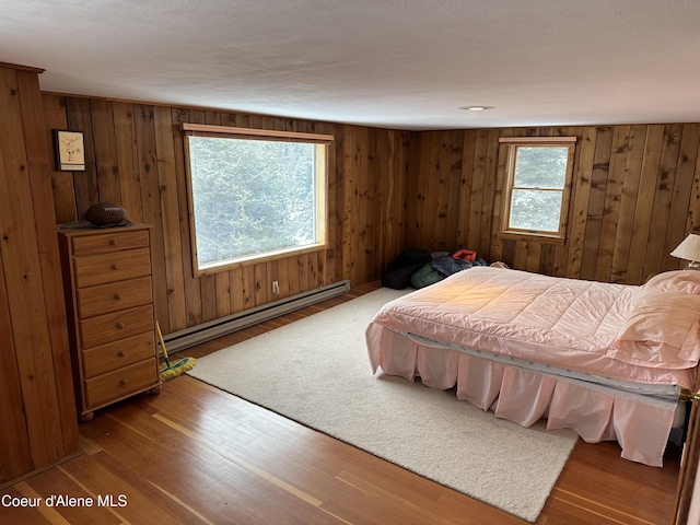 366 Yukon Rd, Bonners Ferry, ID 83805 - bedroom with a baseboard heating unit, wood walls, and wood finished floors