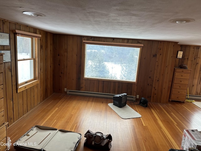 366 Yukon Rd, Bonners Ferry, ID 83805 - exercise area with wood finished floors, healthy amount of natural light, baseboard heating, wood walls, and a baseboard heating unit